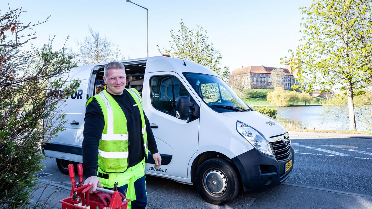 Service technician in a hi-vis vest standing beside a work van